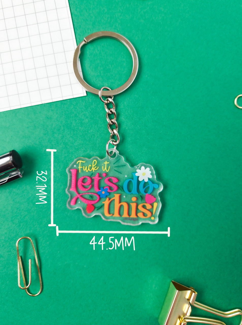 Keychain with colorful text on a green surface with measurements
